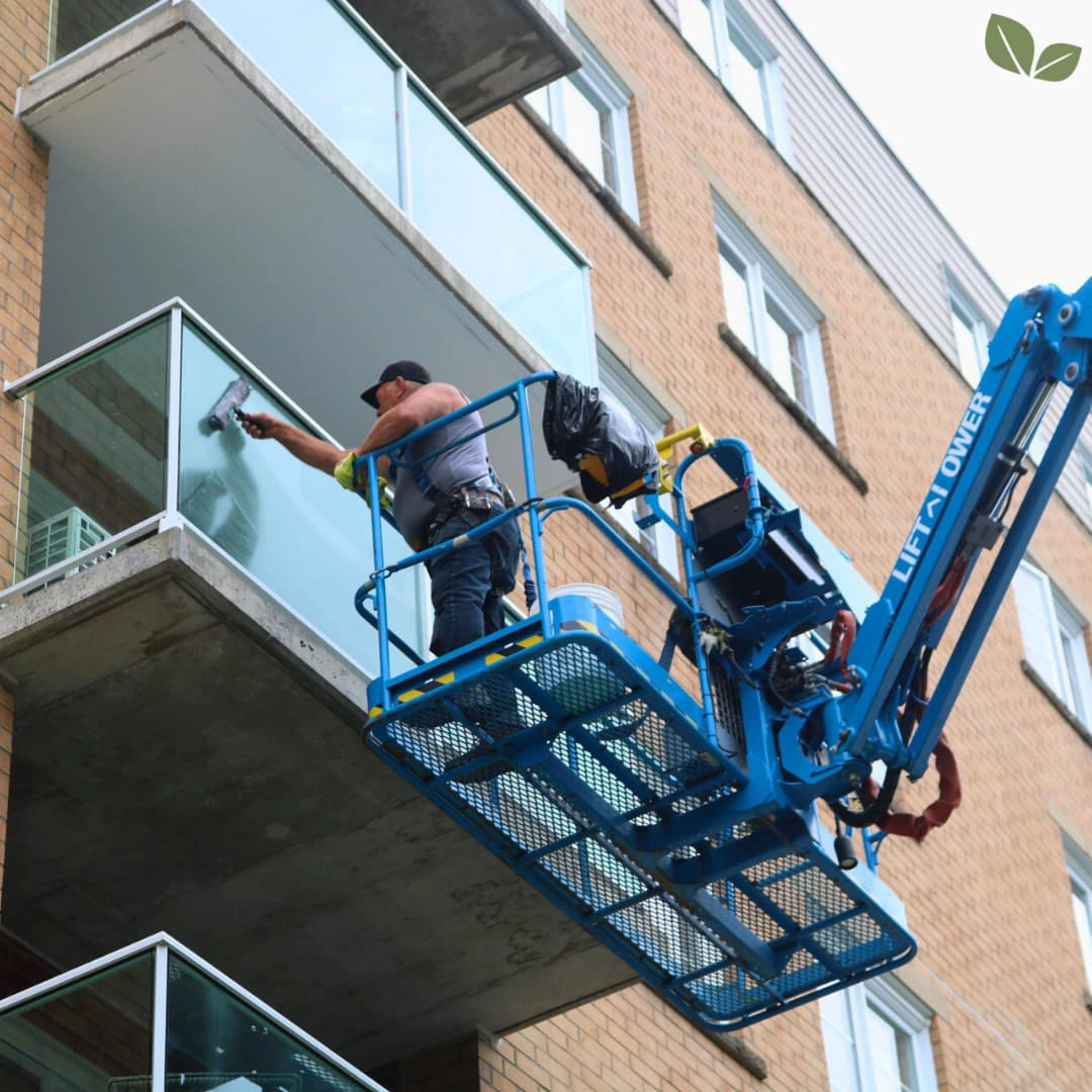 Homa technician cleaning high-rise balcony glass using a lift platform and professional window washing tools