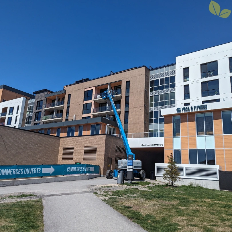 Homa technicians performing high-rise commercial window cleaning using a boom lift on a multi-story building