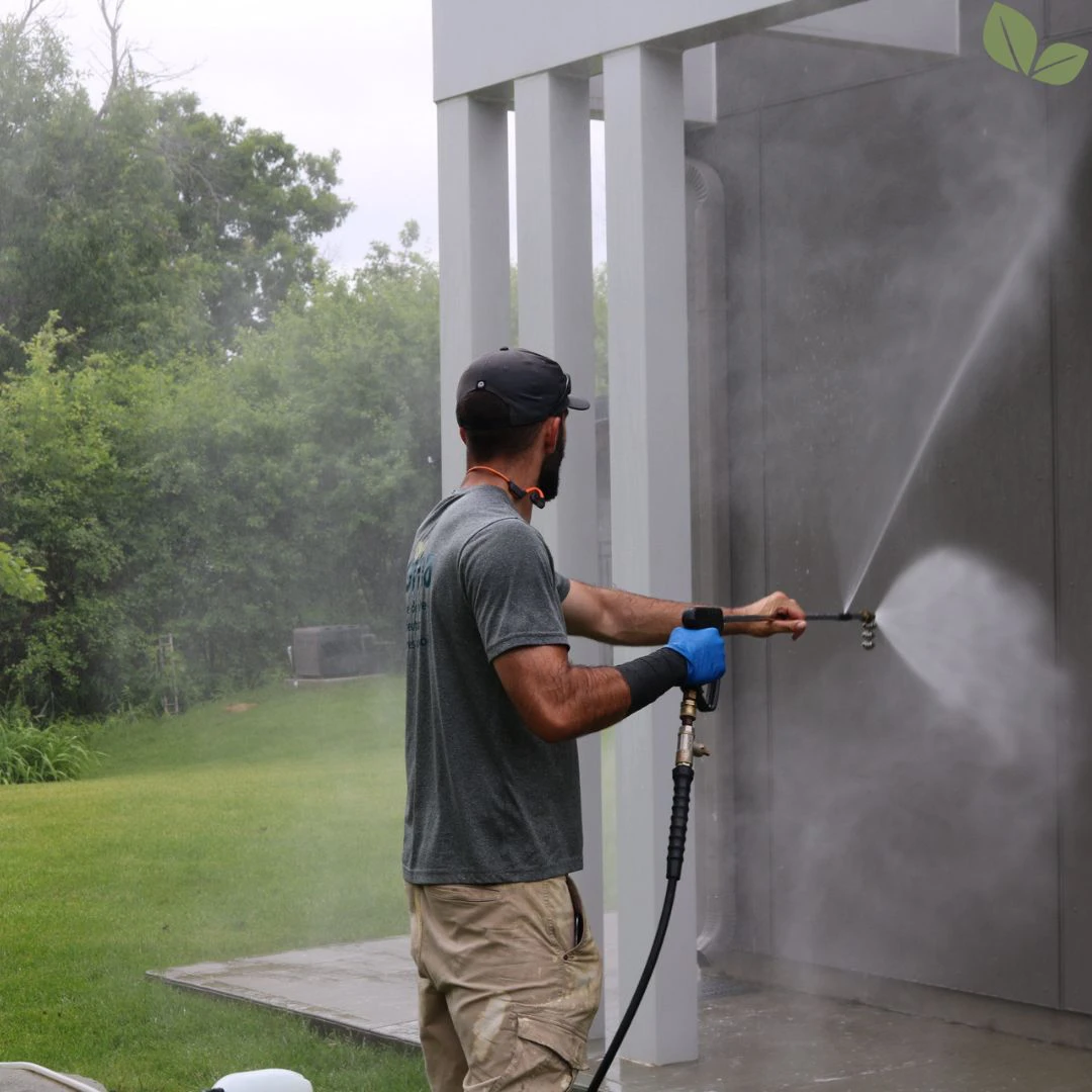 Technician pressure washing exterior building wall using professional equipment