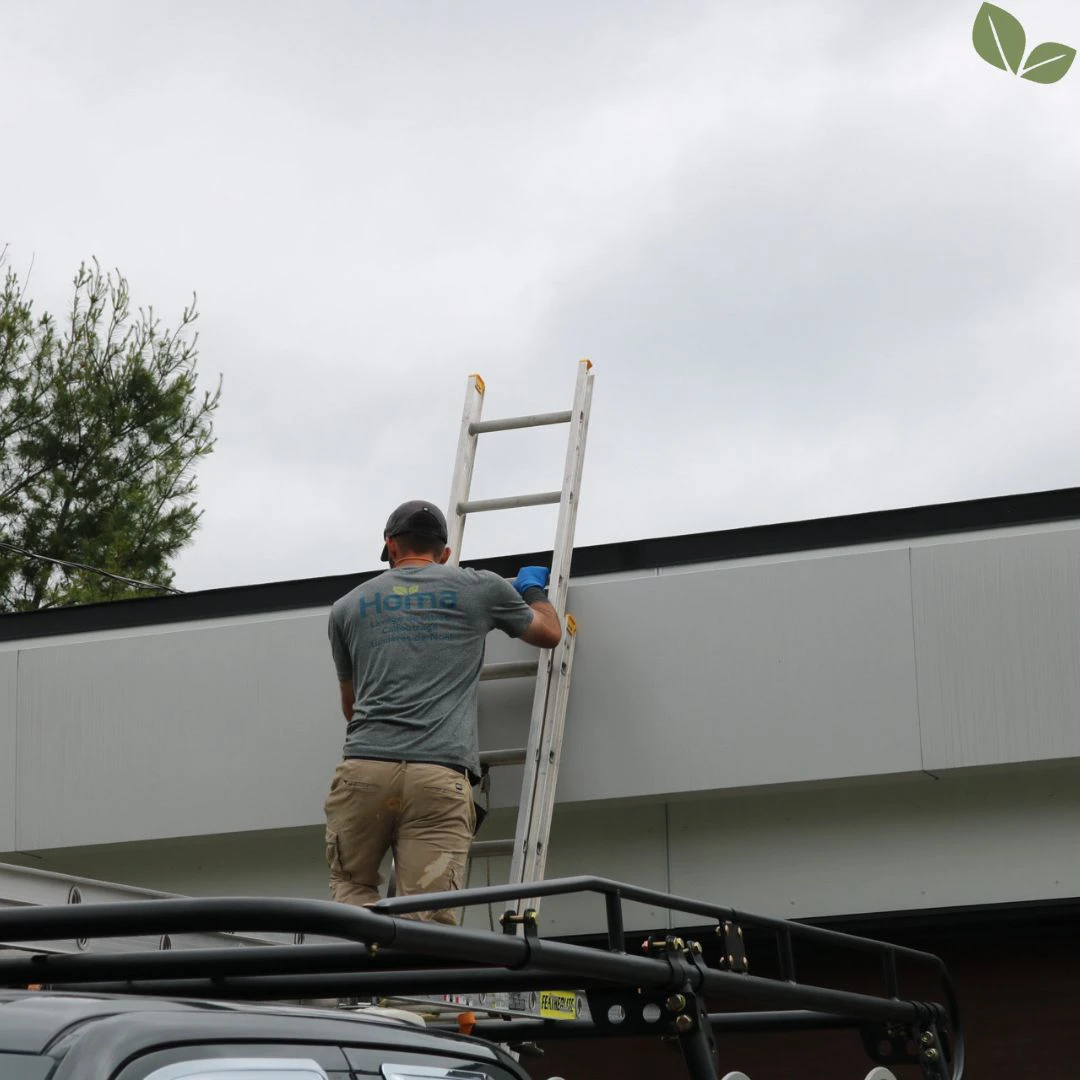 Technician accessing commercial roof edge for exterior maintenance service