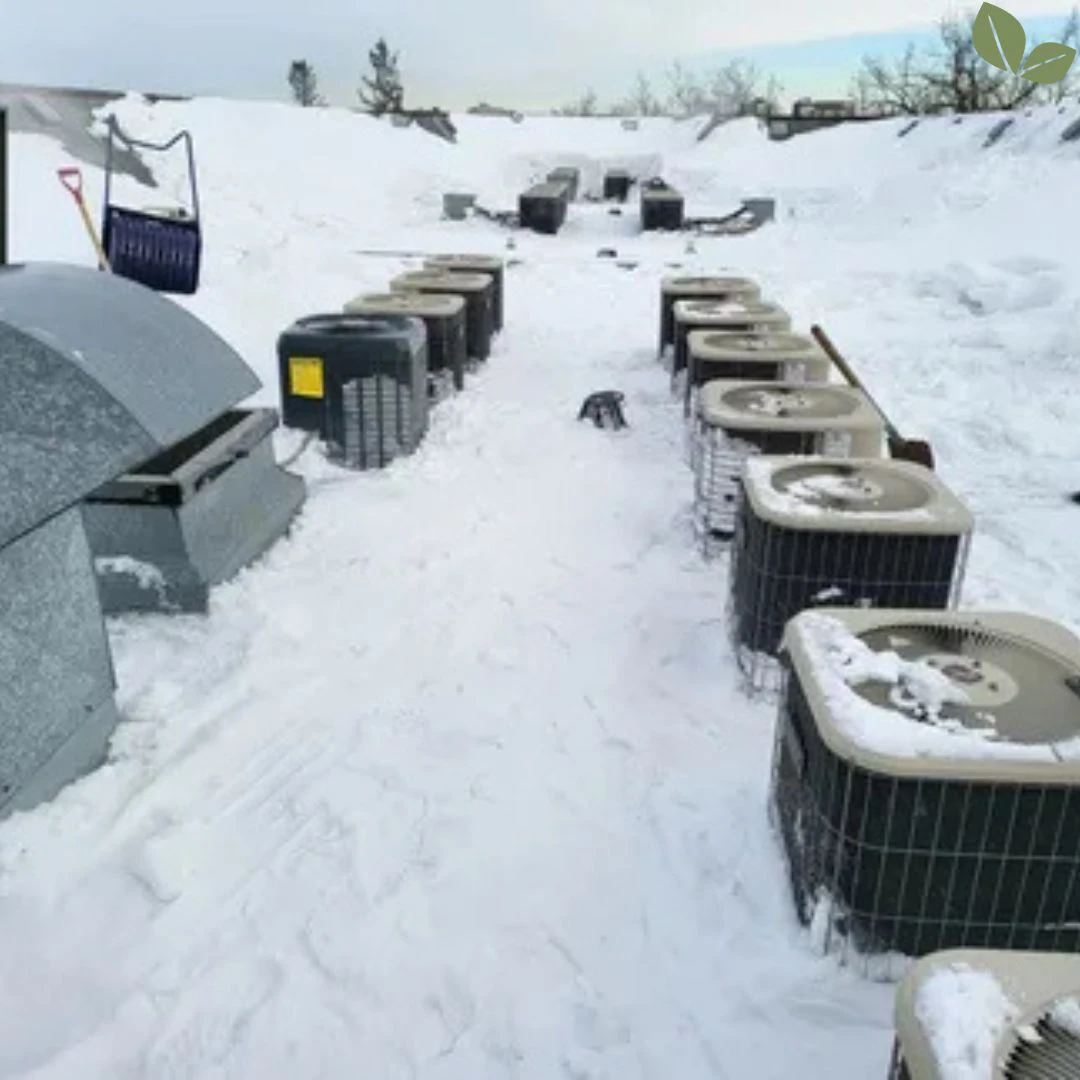 Snow cleared from a commercial flat roof around rooftop HVAC units to maintain airflow and prevent equipment damage