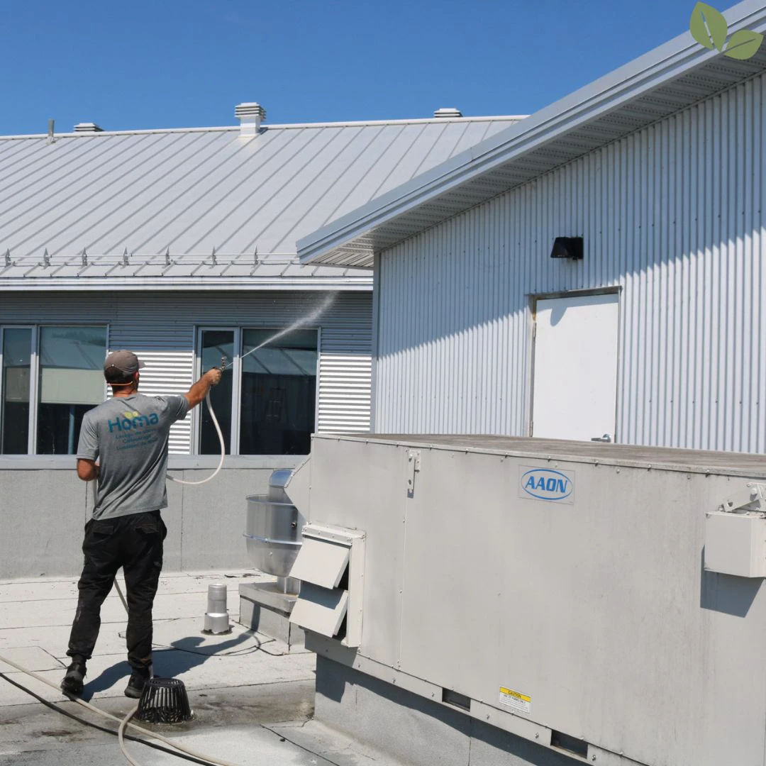 Technician performing commercial roof soft wash on metal roof using low-pressure treatment