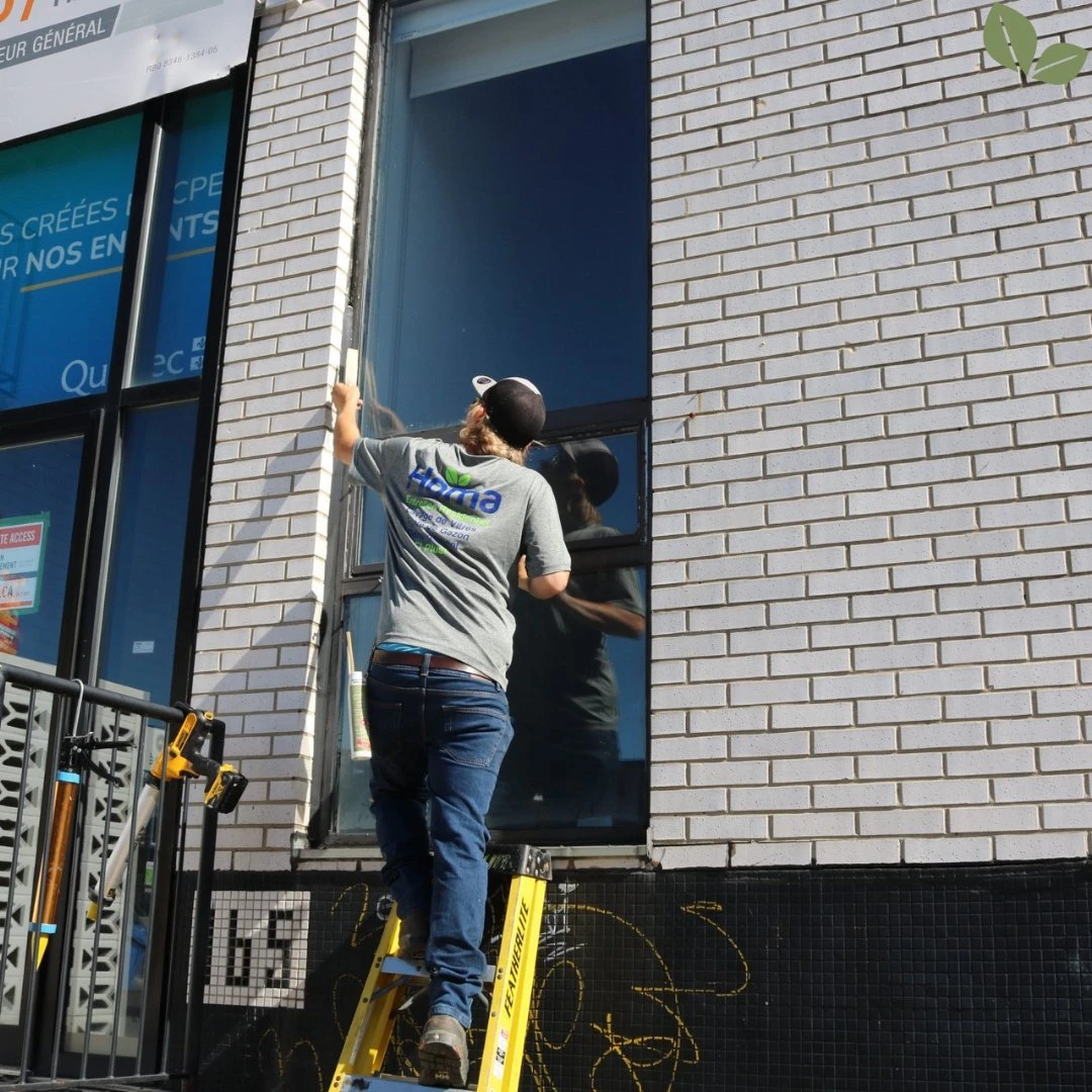 Technician applying exterior caulking around a commercial window to seal and protect the building.