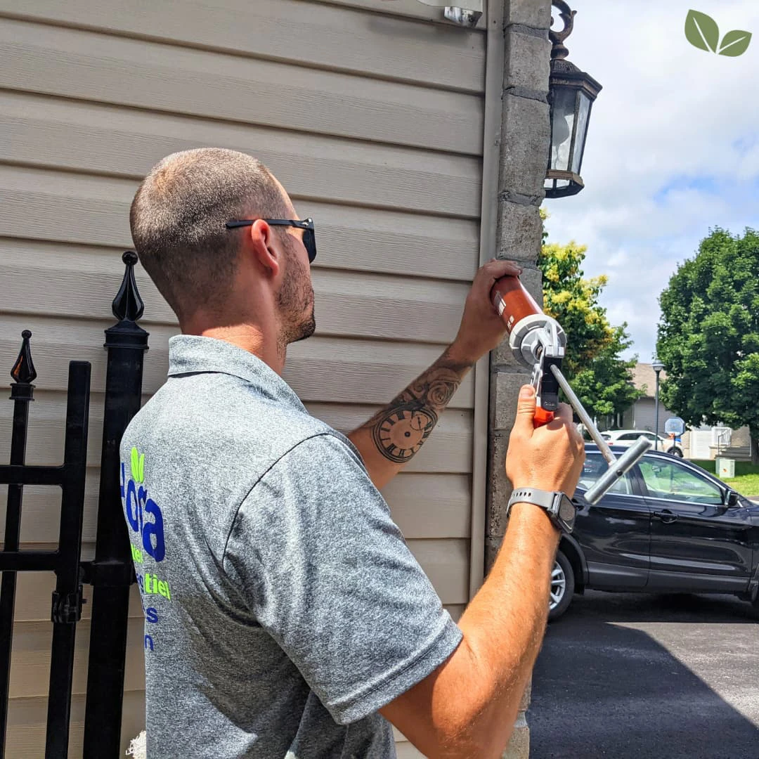 Homa technician applying exterior caulking around residential windows and trim