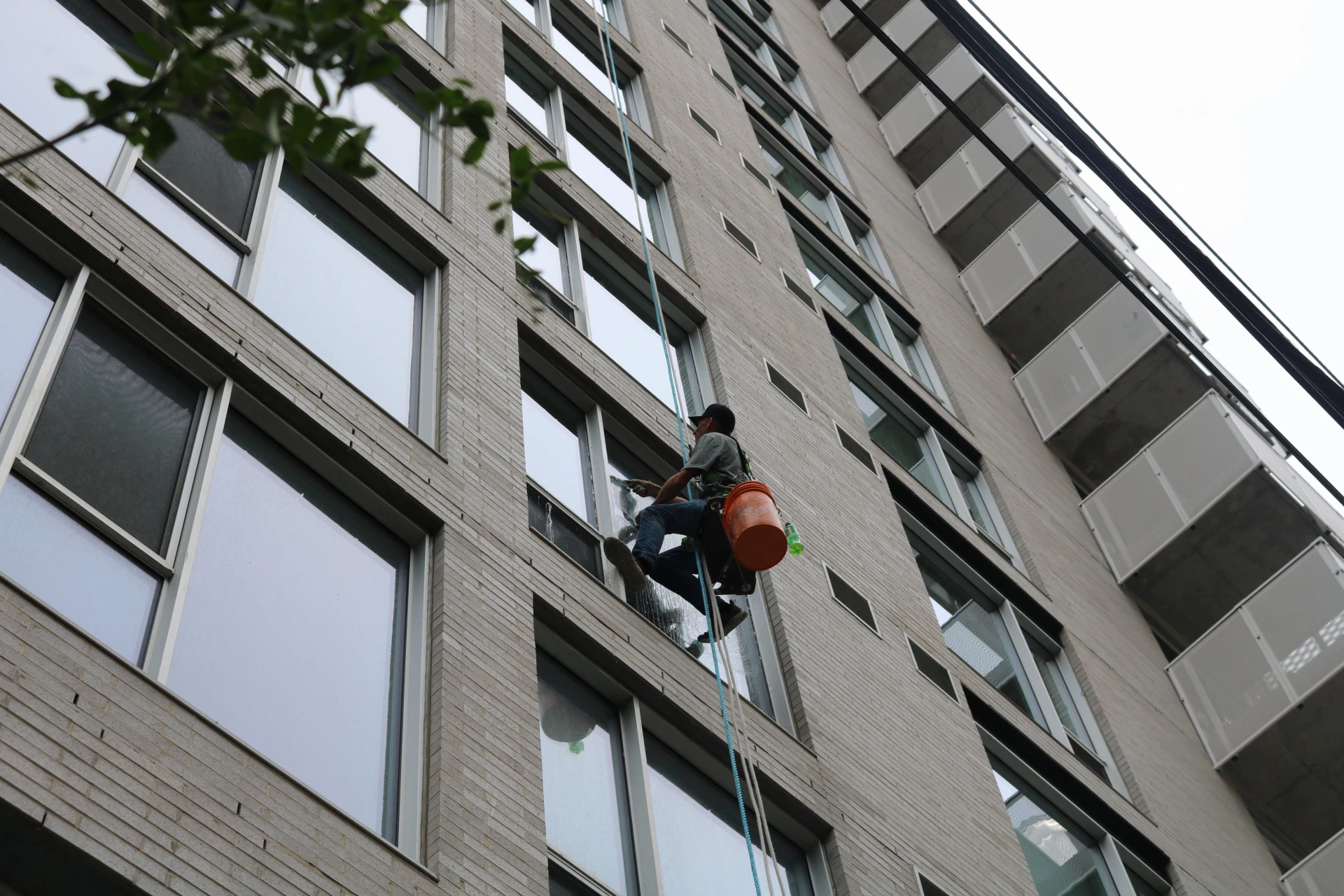 Homa technician performing high-rise residential window cleaning using rope access on an apartment building