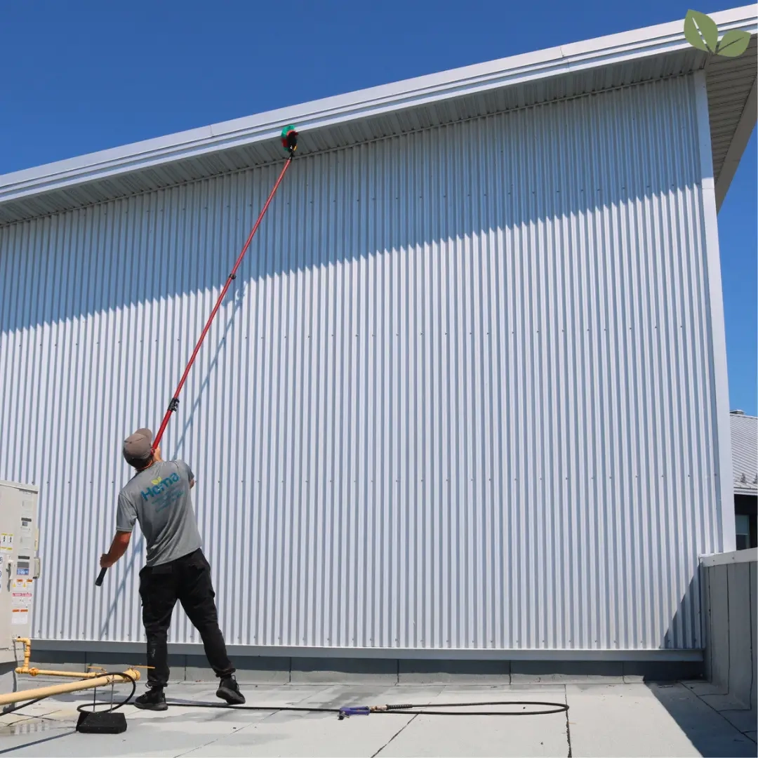Homa technician performing soft wash exterior cleaning on commercial building siding