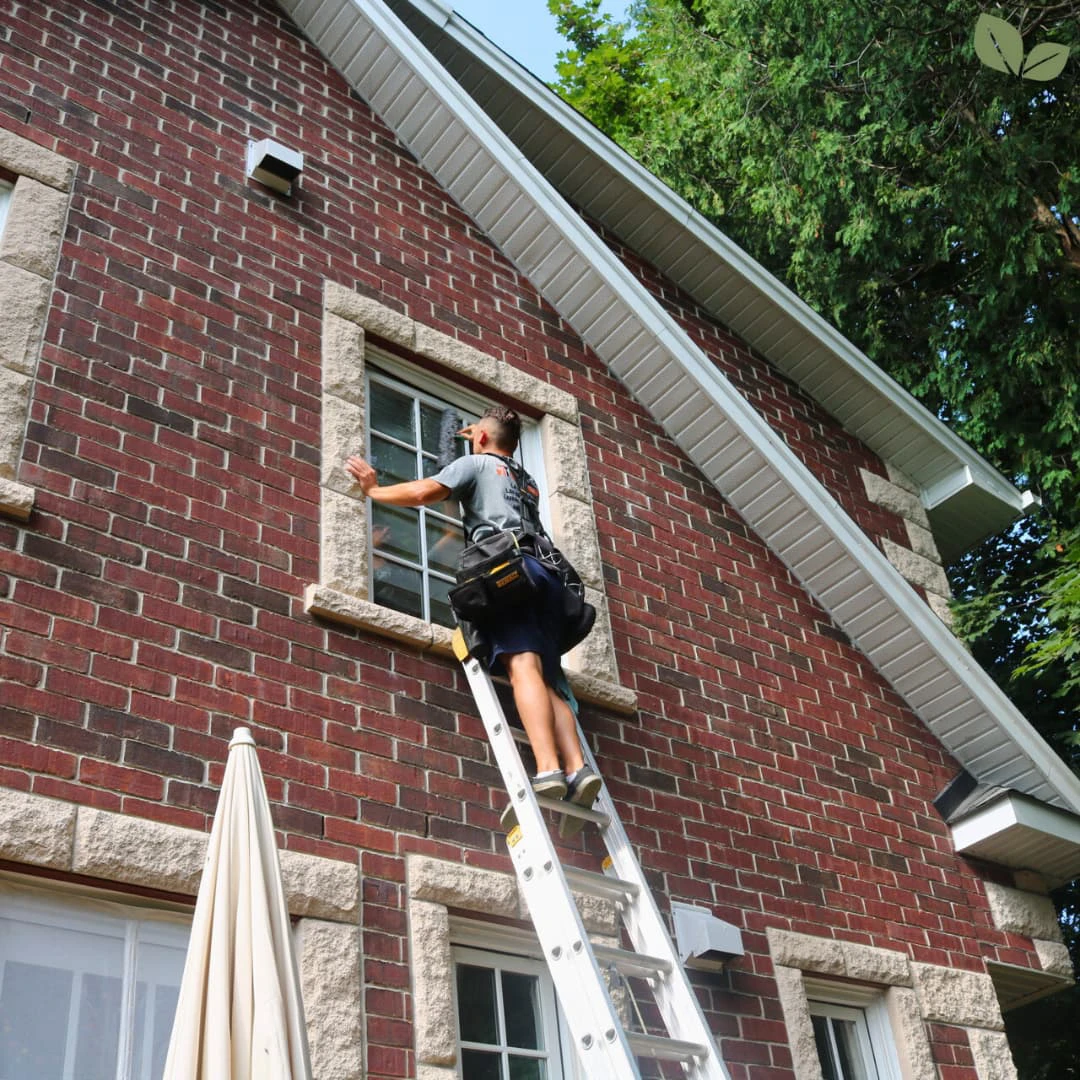Technician cleaning residential window frame and glass