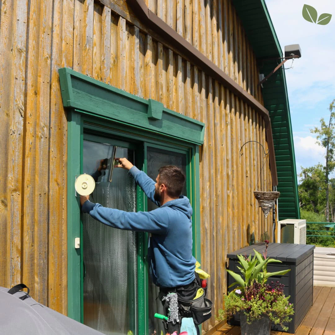 Technician cleaning exterior window on residential home